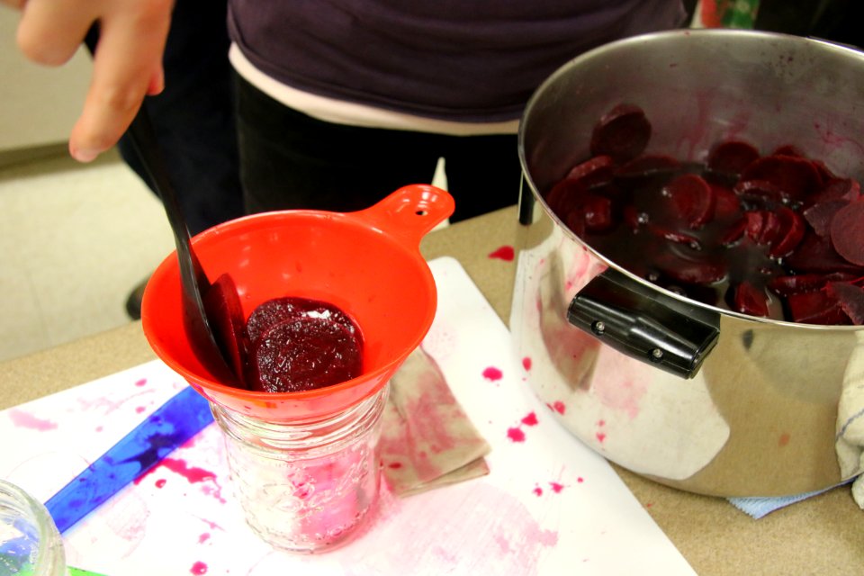 Adding beets to jars from pan