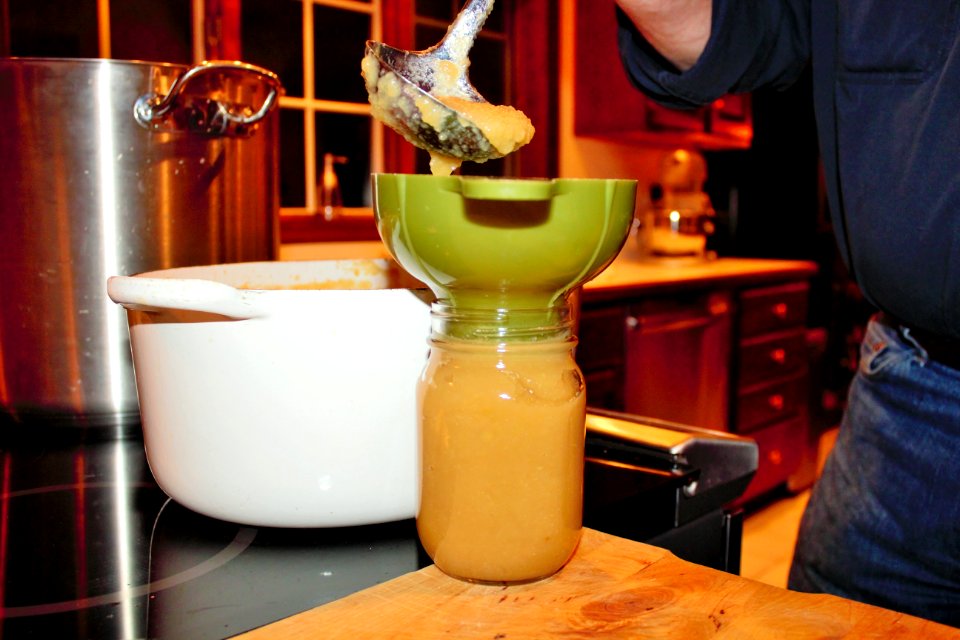 Applesauce being ladled into canning jar