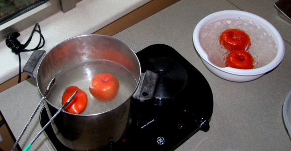 Dipping tomatoes in boiling water, followed by ice bath, for easy peeling photo