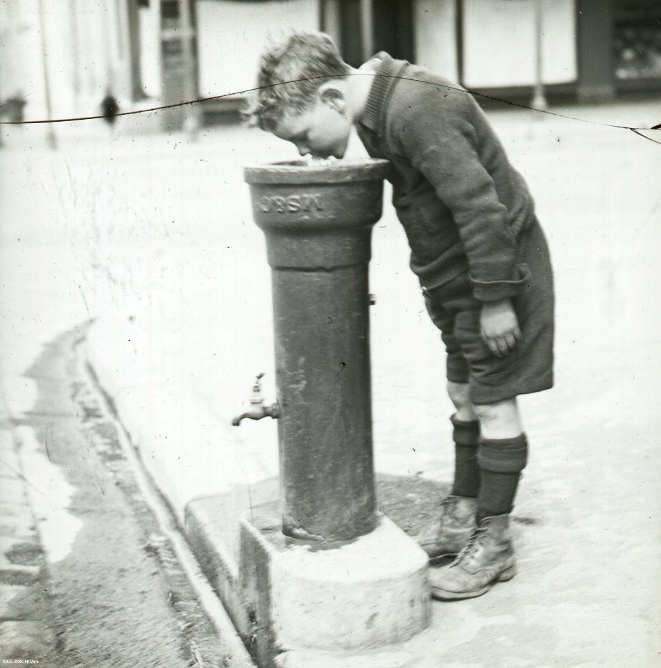 Boy drinking from Fountain Pipe c1920