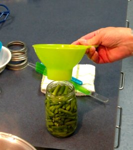 Using funnel to fill jar with green beans
