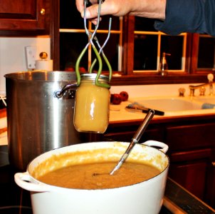 Jar lifter being used to move mason jar into canner photo