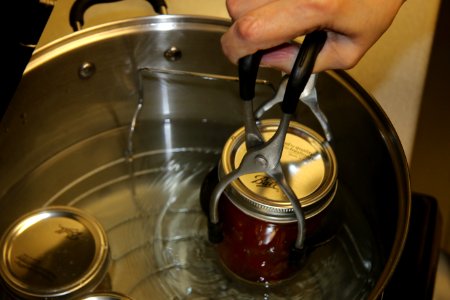 Removing salsa from boiling water canner using jar lifter photo