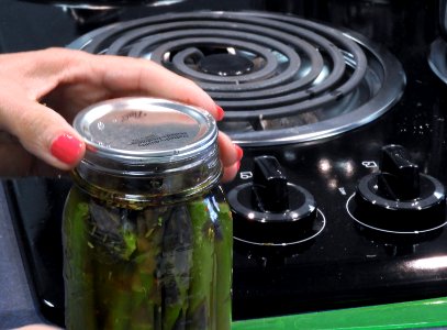 Placing lid on pickled asparagus photo