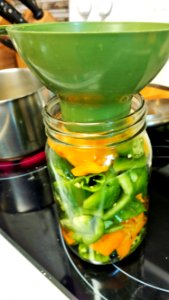 Adding hot vinegar solution to pickled peppers