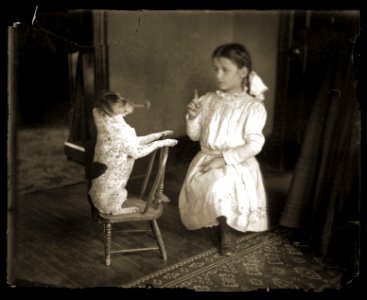 A girl playing with a dog, c1913