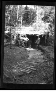 soldiers in fornt of a hut in the forest