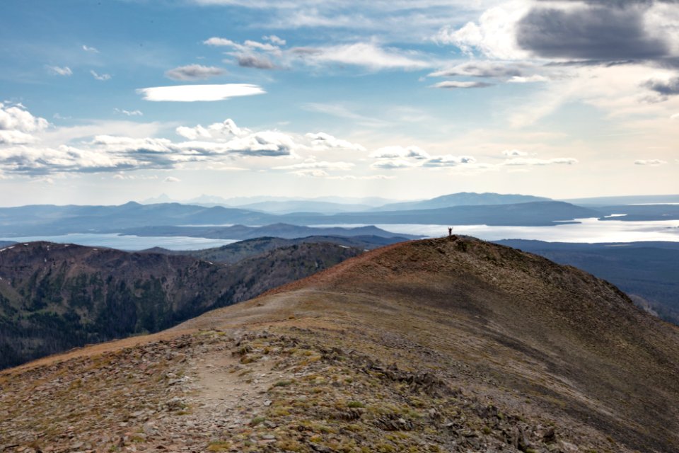 Hiker celebrating on the top of Avalanche Peak with the Teton Range in the distance photo