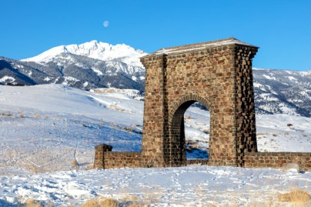 A winter scene at Roosevelt Arch with a setting moon