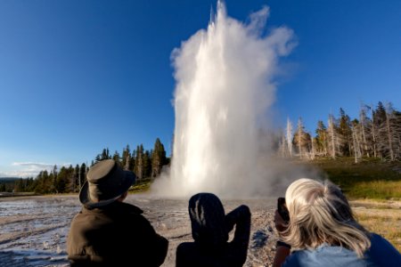 People watch a Grand Geyser Eruption on a bluebird evening