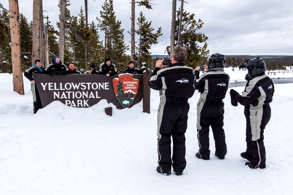 Snowmobiler group photo at the South Entrance sign