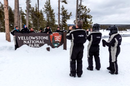 Snowmobiler group photo at the South Entrance sign