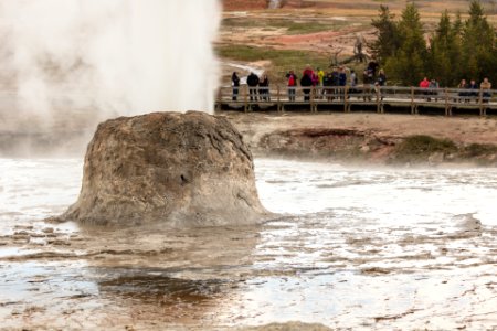 Beehive Erupts as a group of people watch from across the Firehole River