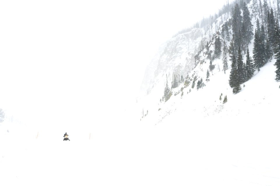 Snowmobiler riding westbound over Sylvan Pass during a snow storm