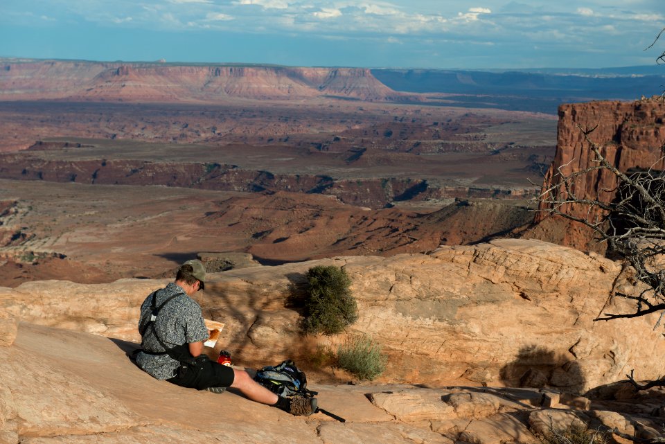 Community Artist Anthony Lott paints at Mesa Arch