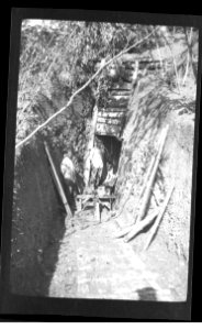 two men and a dog at the entrance of an underground shelter