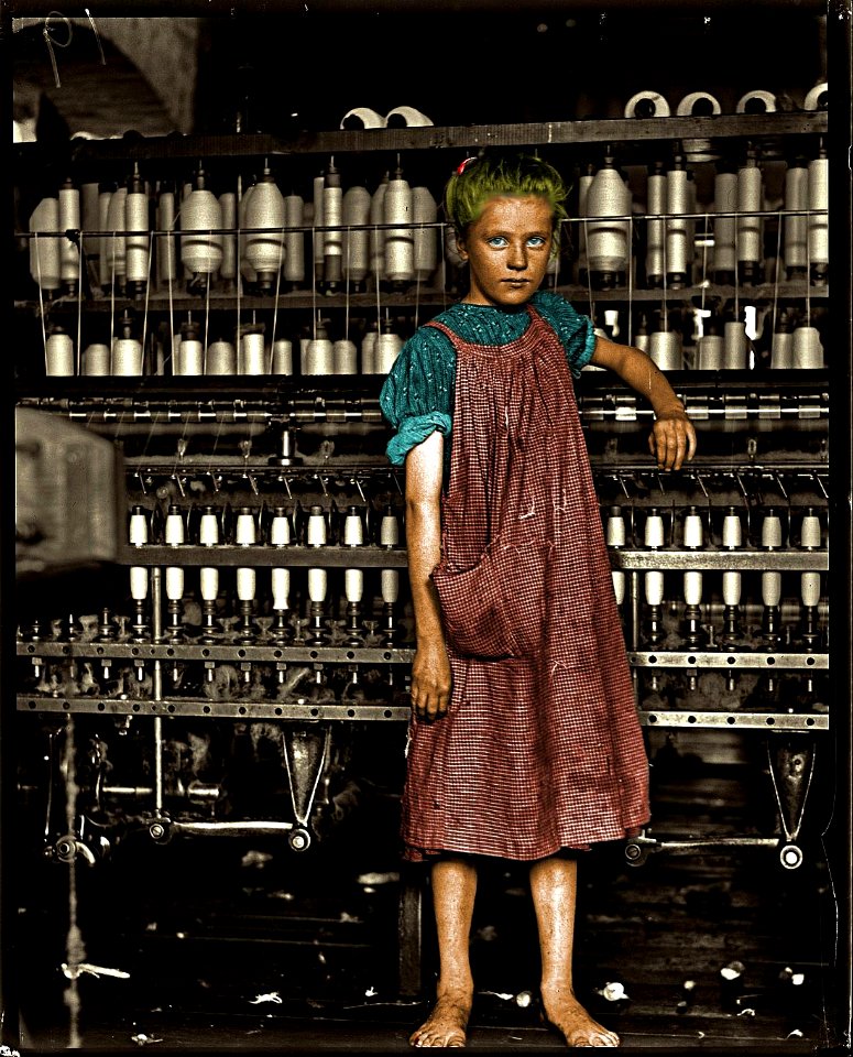 Child Labor:  A barefoot girl works in a New England textile mill, 1910. (Colorized)
