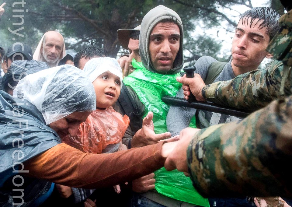 Thousands of people braved torrential downpours to cross Greece's northern border with Macedonia