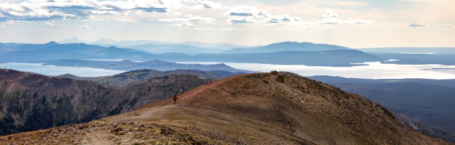 Hiker headed down from the top of the Avalanche Peak Trail with the Teton Range in the distance (panorama) photo