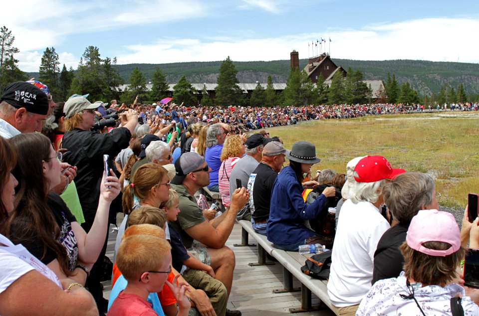 Visitors watching Old Faithful Geyser erupting. Old Faithful Inn in background 5640