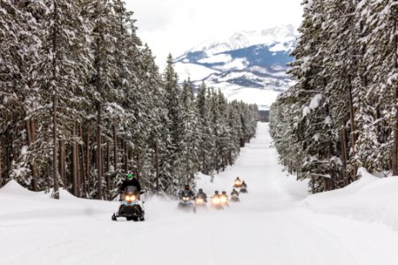 Snowmobiles riding the park road with the Tetons in the background