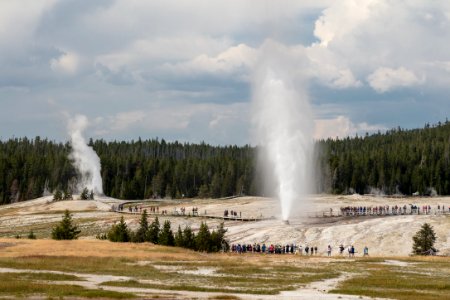 People watching Beehive Geyser erupt with Lion Geyser in the backgroup photo