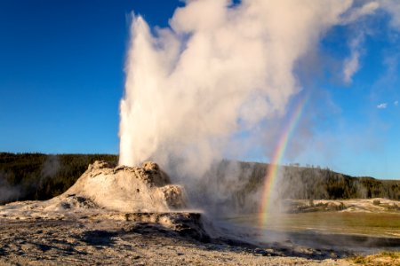 Castle Geyser eruption with rainbow