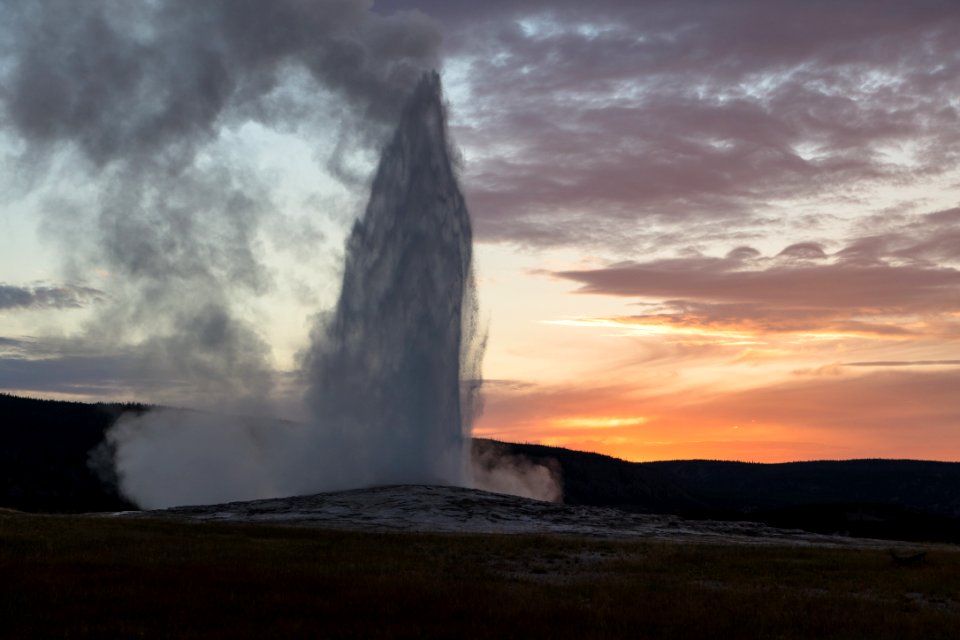 Old Faithful eruption at sunset