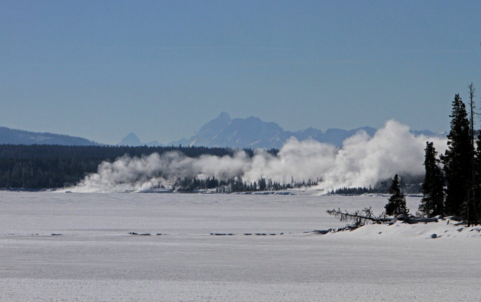 View across Yellowstone Lake to West Thumb Geyser Basin.  Grand Teton Mountain Range 50 miles in the distance