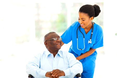 beautiful african nurse taking care of senior patient in wheelchair photo