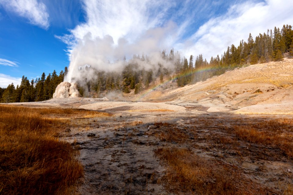 Fall morning Lone Star Geyser eruption with rainbow and outflow