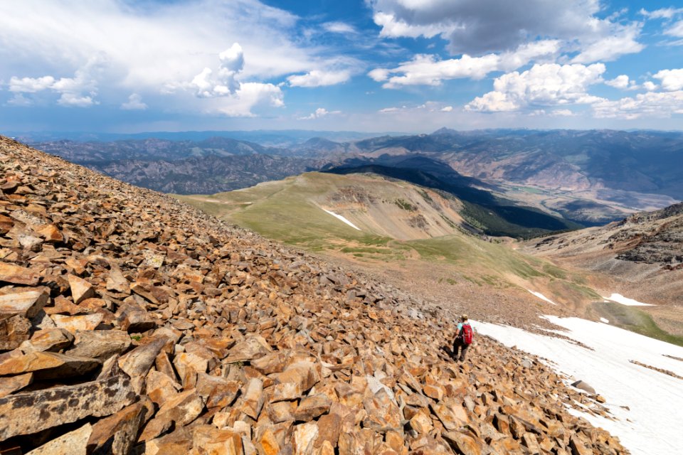Hiker descending north face talus slope on Electric Peak