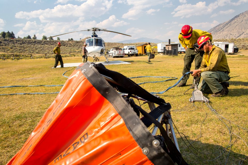 Helitack crew members rig a helicopter for bucket drops