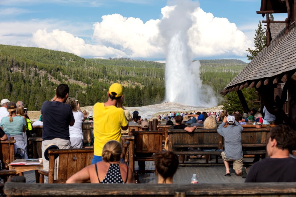 People watching Old Faithful erupt from the Old Faithful Inn