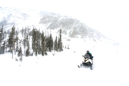 Snowmobiler riding eastbound over Sylvan Pass during a snow storm (2) photo