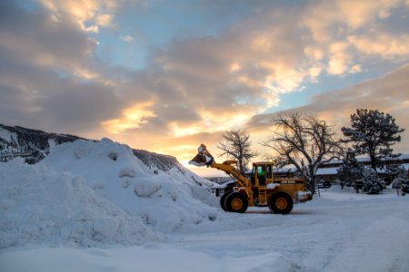 Clearing snow away in Mammoth with a front-end loader at sunrise