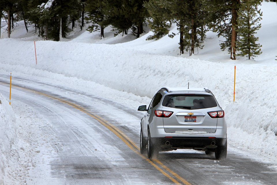 Car driving on Northeast Entrance Road lined with tall snowbanks
