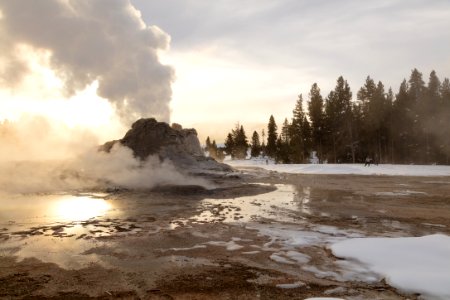 Skiers near Castle Geyser during steam phase at sunrise photo