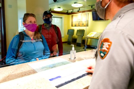 Chatting with a ranger through a plexiglass window at a visitor center desk