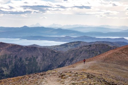 Hiker headed down from the top of the Avalanche Peak Trail with the Teton Range in the distance photo