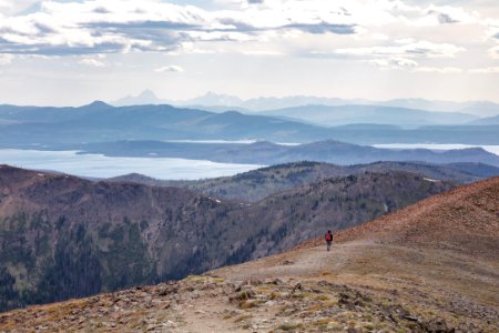 Hiker headed down from the top of the Avalanche Peak Trail with the Teton Range in the distance