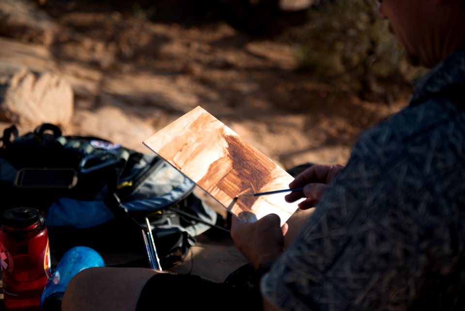 Community Artist Anthony Lott paints at Mesa Arch