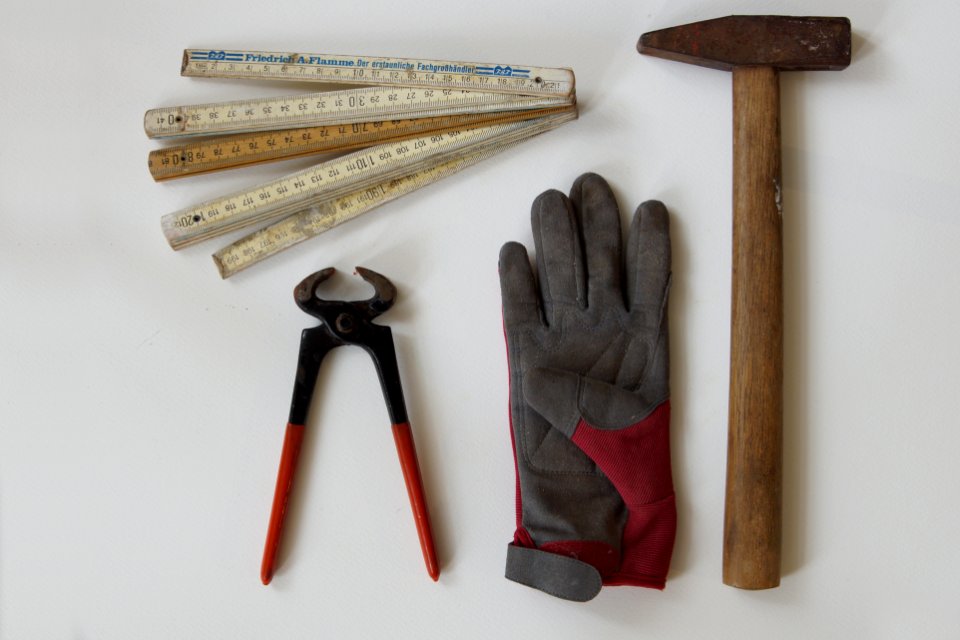 Zange, Arbeitshandschuh, Hammer und alter Zollstock