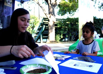 Ojai, Calif. (March 18, 2017) - Ventura Fish and Wildlife Office biologist Karen Sinclair gives native pollinator seeds to a young visitor during an event at the Libbey Bowl celebrating women in science, and longtime condor advocate Jan Hamber.