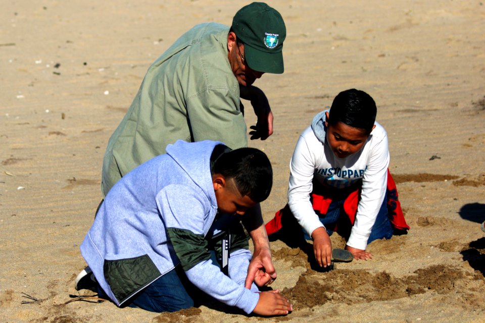 Fish and wildlife biologist Shawn Milar lends a helping hand to two second grade students from Santa Rita Elementary School.
