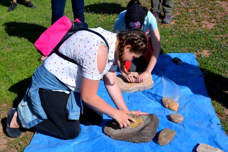 Students ground corn using a mano and metate at the Flaming Gorge STEM Day archaeology station. Flaming Gorge Dam, UT. Photo by Markel Baker, BLM UTSO