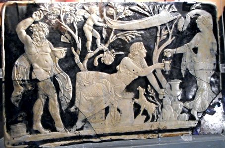 Panel with Maenad pouring wine for Ariadne in the presence of a Satyr dancing between trees from which hang objects of the cult of Dionysos - glass cameo (1st century AD) from Pompeii - Exhibition "Myth and Nature" at Archaeological Museum of Naples, unti photo