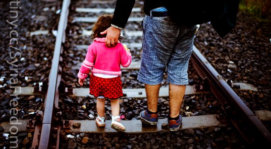 A refugee helps his daughter to run at the railway track after he crossed the Serbian-Hungarian border photo