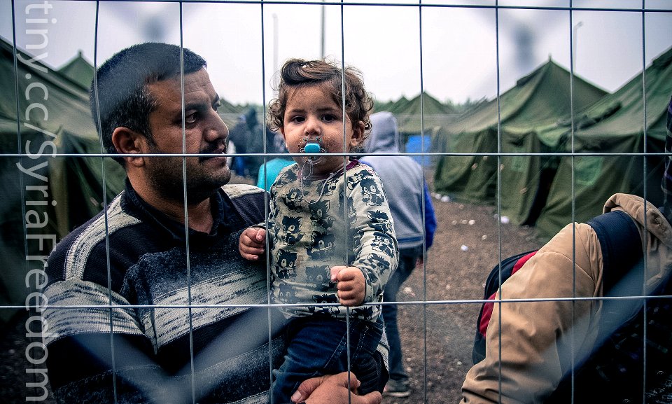 A Syrian refugee carrying his child
