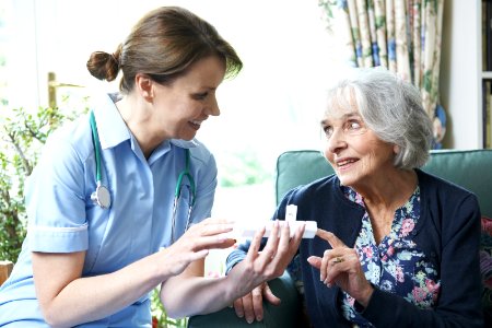 Nurse Advising Senior Woman On Medication At Home photo